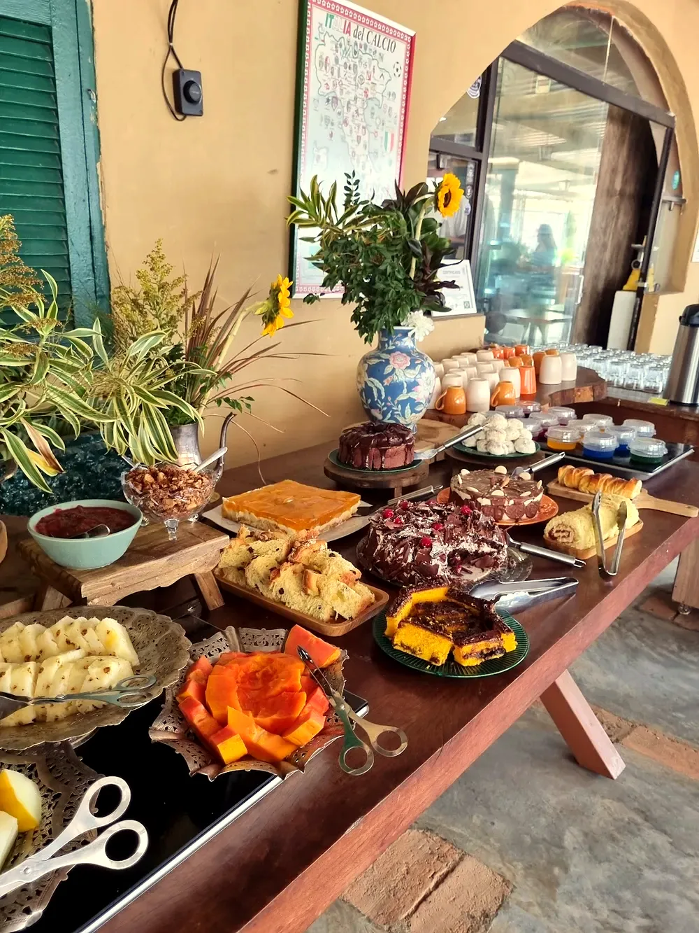 Mesa posta com bolos, pães e flores para um evento na Casa do Pão