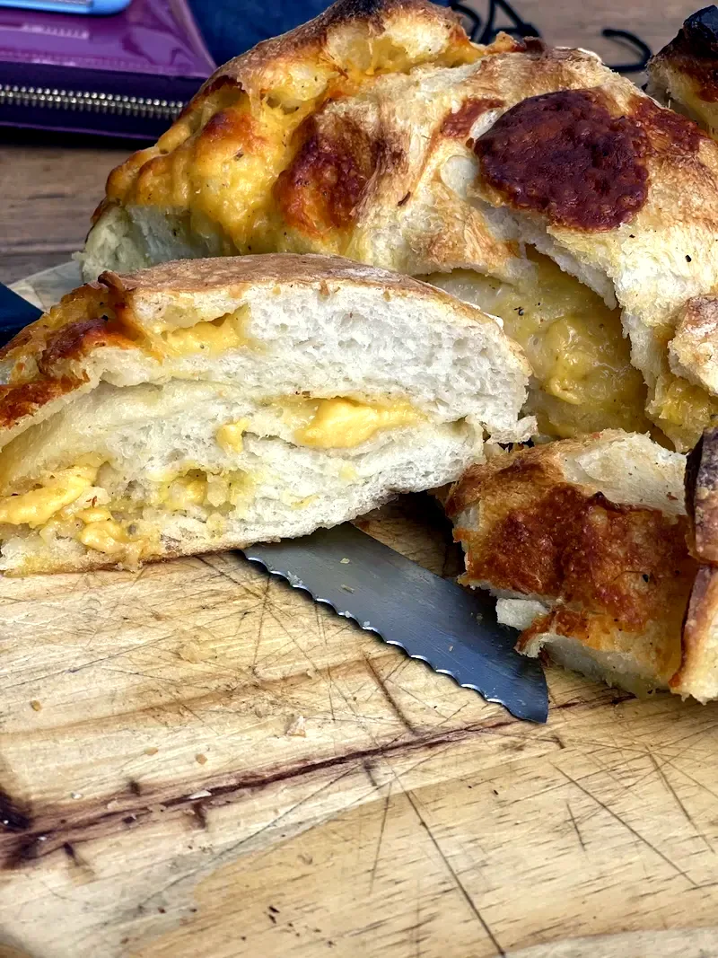 Pão recheado com queijo, cortado sobre tábua de madeira
